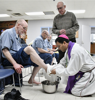 Bishop Fernandes washing feet at a prison on Holy Thursday (Photo by Ken Snow)